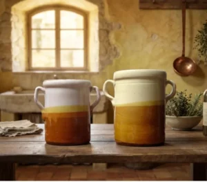 Salaturi in ceramica calabrese su tavolo rustico Due salaturi tradizionali in ceramica calabrese appoggiati su un tavolo di legno all'interno di una rustica cucina di campagna.