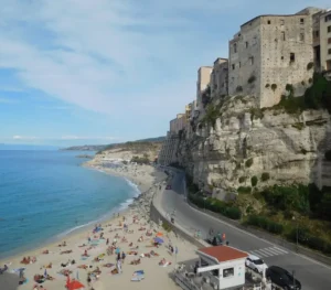 Tropea – I palazzi sulla rupe e la spiaggia sottostante Veduta panoramica dei palazzi nobiliari di Tropea costruiti a picco sulla rupe di tufo sopra la spiaggia bianca.