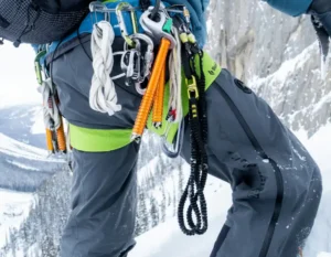 Dettaglio dell'imbragatura da arrampicata con moschettoni e rinvii agganciati alla cintura.