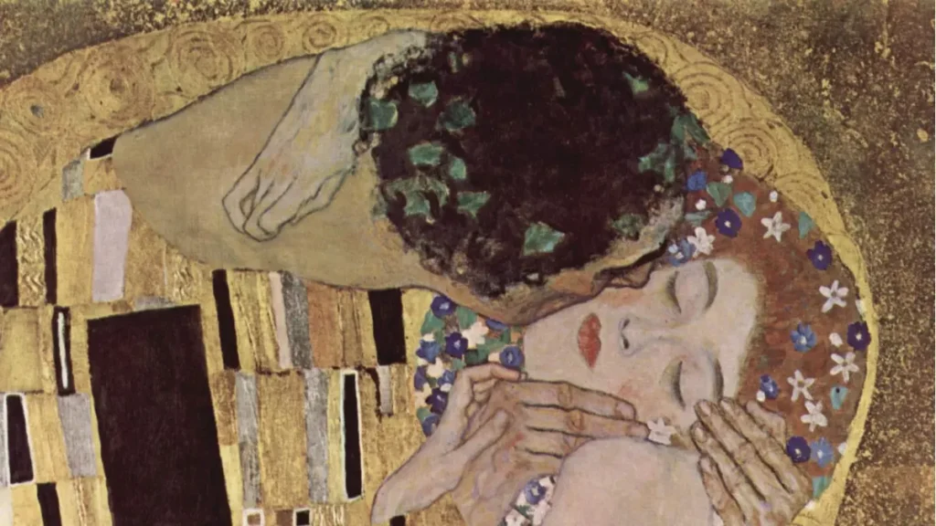 Particolare ravvicinato dei volti e dell'abbraccio nel dipinto Il Bacio di Gustav Klimt, immagine in evidenza.