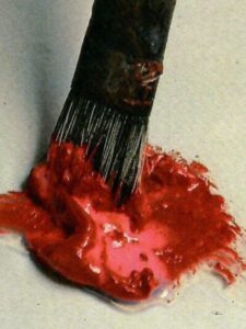 Stesura dei colori acrilici Primo piano di colore acrilico rosso con pennello da pittura