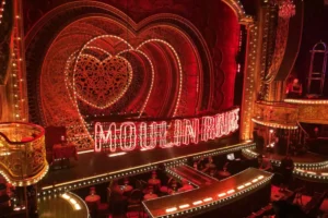 Red neon sign and glowing stage setup for Moulin Rouge The Musical on Broadway