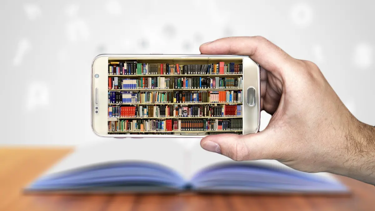 Mano che tiene uno smartphone con lo schermo che mostra una scaffalatura piena di libri, simbolo di lettura e cultura digitale su Millefogli Smart.